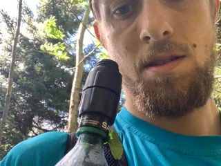 A photo of Joe with a Sawyer watter bottle with a leaf hanging out of it.
